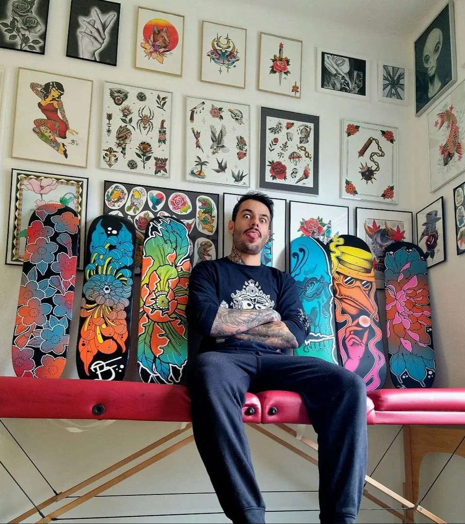 Ben assis dans son studio à Lausanne, devant ses planches de skate peintes et ses dessins