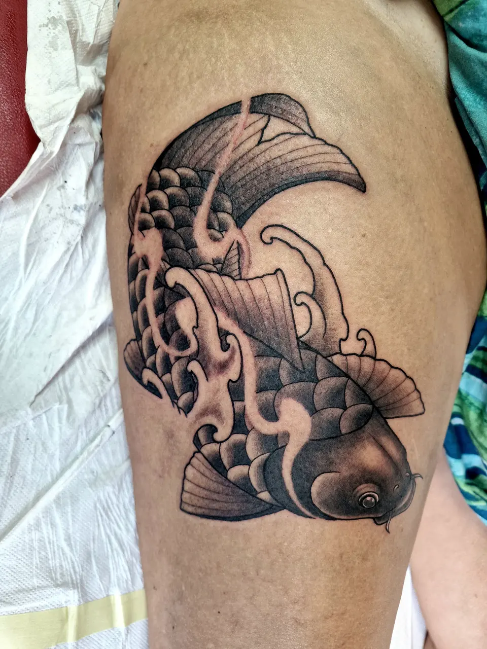 Carpe koï et vagues en noir et gris, sur la cuisse