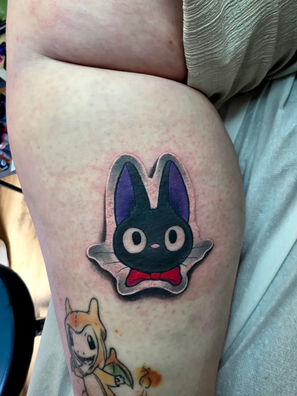 Jiji, le chat noir au nœud rouge, tatoué sur le bras