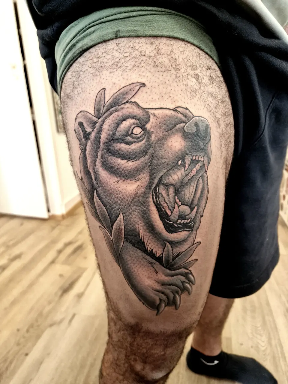 Ours rugissant en noir et gris, tatoué sur la cuisse