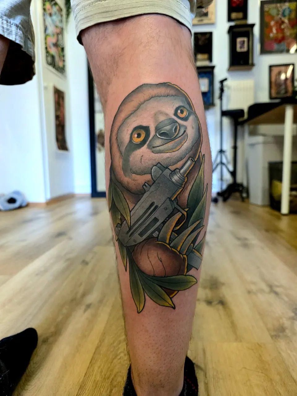 Paresseux entouré de feuilles, tatoué sur le mollet